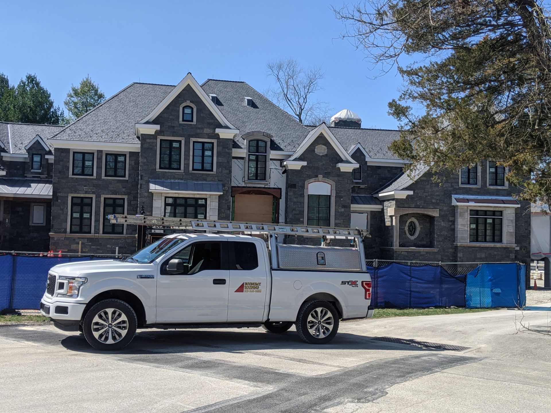 Mansion construction progress with roofing and siding by Economy Roofing